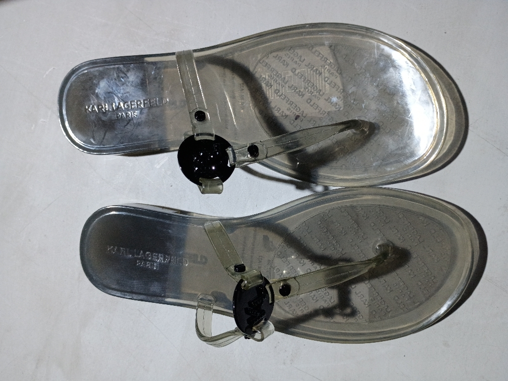 KARL LAGERFELD PARIS sandal features a T-strap silhouette, an open toe and a crystal embellished logo. Size 7M