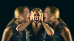 A woman is screaming with her hands in her ears, experiencing a comprehensive journey within while exploring her inner terrain.