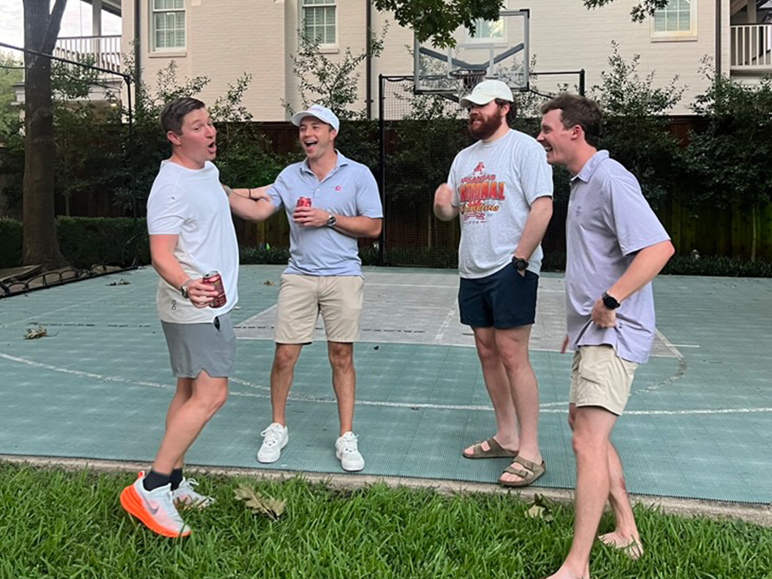 Four men at PCPC's Young Adult Ministry laughing and talking together on an outdoor basketball court.